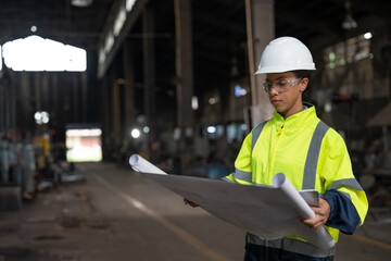 Portrait African American female engineer holding blueprint working in heavy metal industrial...
