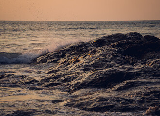 A large rocks surrounded by waves of the ocean