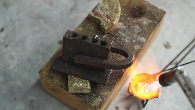 Heating with a flame jet of a metal billet of a silver ring. The work of a jeweler in the workshop
