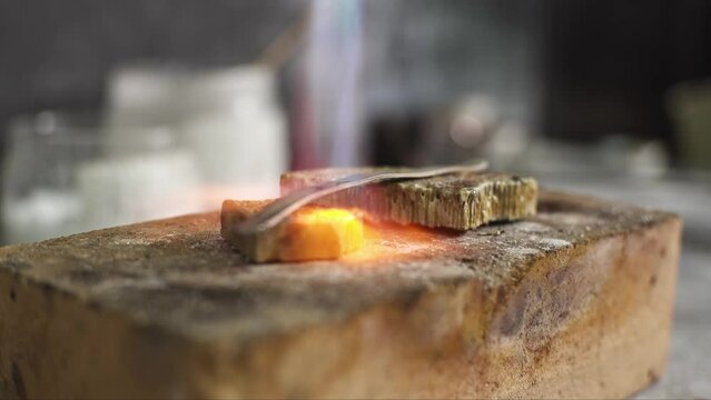 Heating with a flame jet of a metal billet of a silver ring. The work of a jeweler in the workshop