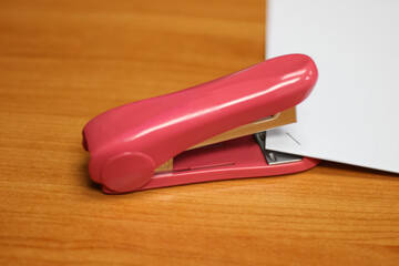 Photo of Pink stapler put on the table in office, stapler is a device used in schools or offices