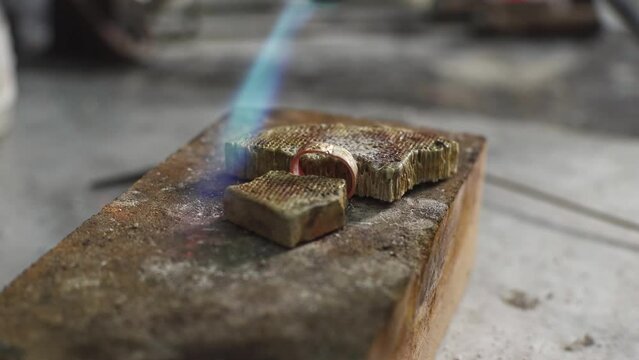 Heating with a flame jet of a metal billet of a silver ring. The work of a jeweler in the workshop