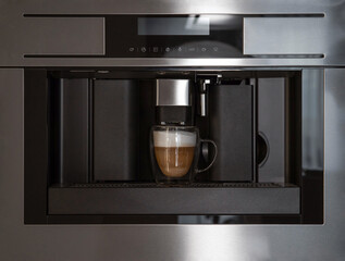Built-in coffee machine making coffee in glass cup, front view