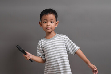 Image of Asian child posing using a magnifying glass on grey background