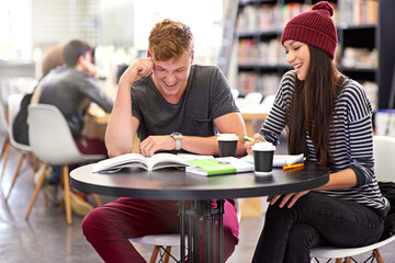 Students, friends and library with book at university for education, learning or teamwork on group project. College, male scholar and happy woman for reading, knowledge or working on assignment