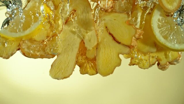 Super Slow Motion Shot of Ginger Slices and Lemon Slices Falling into Water at 1000fps.