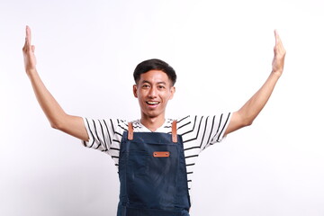 Smiling Asian man in apron indicate something big while holding her palms up. Isolated on white