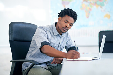 Desk, thinking and black man with laptop, notes or business plan at international agency. Research,...