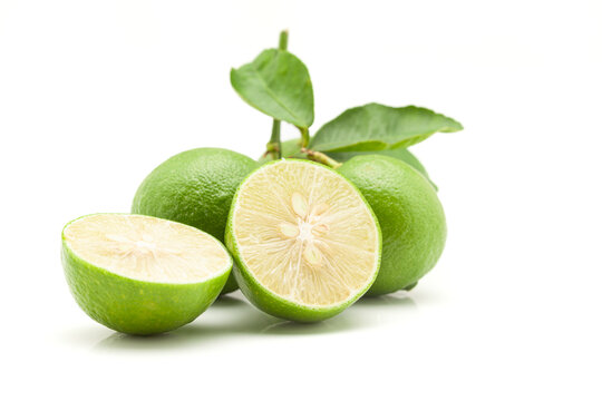 Close-up of fresh green organic whole and sliced lemons (Citrus limon) with leaves isolated on a white background.