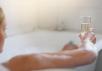 Woman, relax and champagne in bubble bath for luxury, wellness and zen with self care. Water, hygiene and arm in bathroom for calm, female person or alcohol on weekend in Europe for vacation in hotel