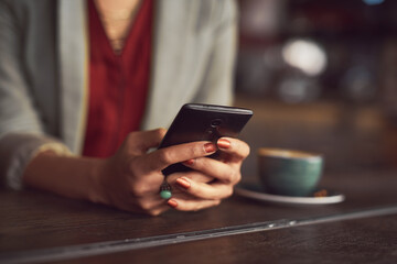 Woman, hands and typing with phone at coffee shop for research, social media or browsing at indoor restaurant. Closeup of female person or employee on mobile smartphone, texting or chatting at cafe