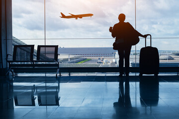 travel by plane, woman passenger waiting in airport, silhouette of passenger in airport watching...