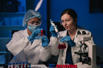 Team of biochemical research scientists working with a microscope for vaccine development.