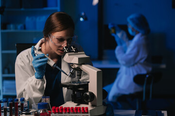 Team of biochemical research scientists working with a microscope for vaccine development.