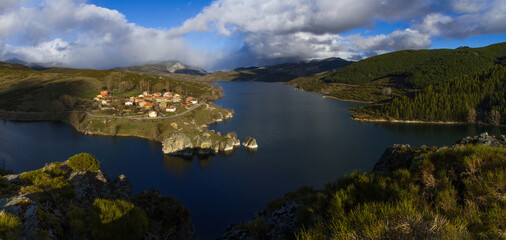 Beautiful panoramic landscape of mountain village on the slope of a swamp. Rural town of Alba de los Cardaños next to the Camporredondo Reservoir in Palencia, Spain