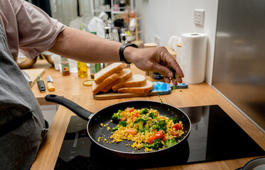 Chef at the kitchen preparing tofu scramble with vegetables