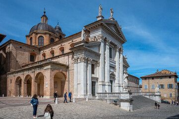 Obraz premium Lovely woman poses in front of a white town building in the province of Pesaro and Urbino