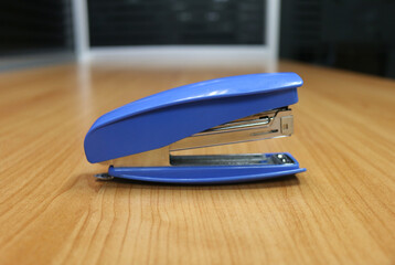Photo of blue stapler put on the table in office, stapler is a device used in schools or offices