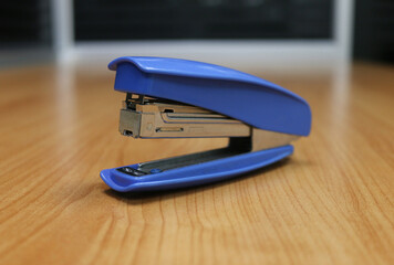 Photo of blue stapler put on the table in office, stapler is a device used in schools or offices