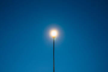 Street lamp glowing under a clear blue sky