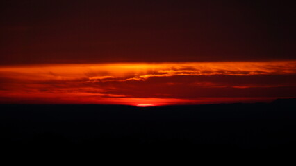 the setting sun rises in the horizon as seen from an airplane