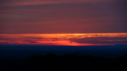 the setting sun over a mountain range from the air at sunset