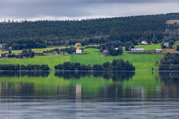 Obraz premium a lake with a house and green grass hill on it