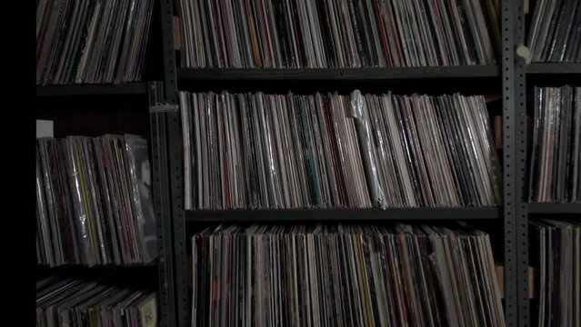 Interior footage of many old audio vinyl records on industrial shelves in a dusty basement