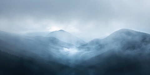 Obraz premium A blurred mountain landscape with mist rolling over the peaks, conveying a sense of mystery and grandeur.