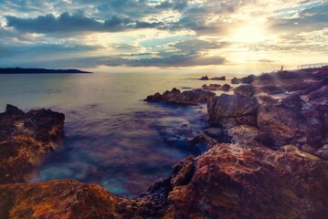 a beach on a cloudy day with lots of rocks in the foreground