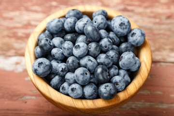 Blueberry berries are in a wooden plate on wooden background. Healthy food and healthy lifestyle.