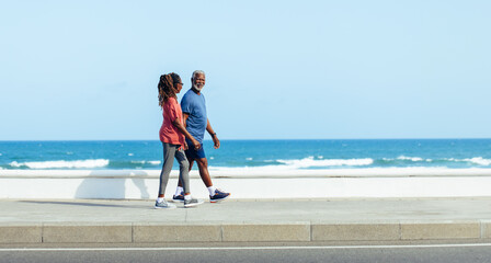 Senior couple smiling and enjoying a leisurely walk by the sea