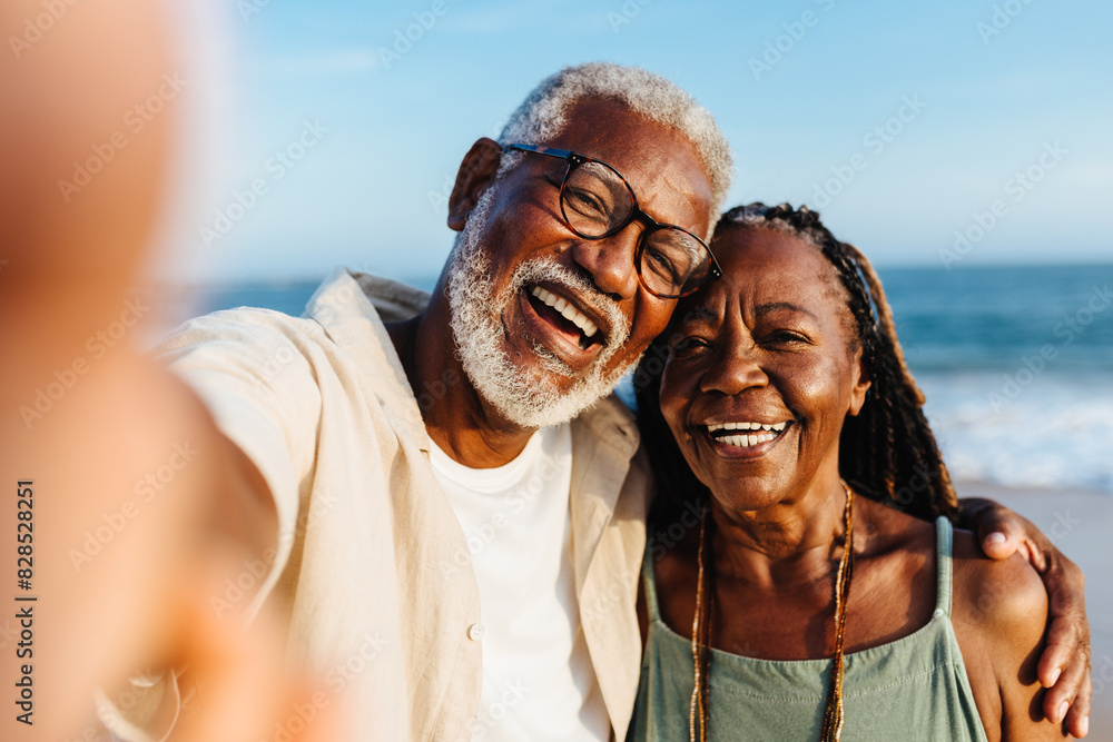 Wall mural Joyful senior African American couple taking a selfie by the sea