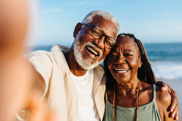 Joyful senior African American couple taking a selfie by the sea - Powered by Adobe