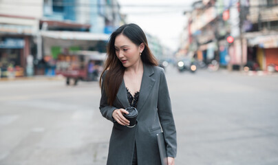 Obraz premium Beautiful Woman Going To Work With Coffee Walking Near Office Building. Business Woman Holding Cup Of Hot Drink In Hand On Her Way To Work On City Street.