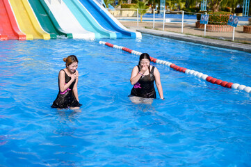 Two women in the swimming pool Both of them wore black swimsuits. They looked like they were having...