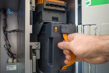 cash messenger's hand inserts a cassette into the deposit module of the cash acceptance terminal....