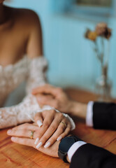 Obraz premium Bride and groom holding hands while seated at a table
