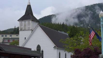 View of St. John's Episcopal Church in Ketchikan, Alaska with trees and mountain behind it