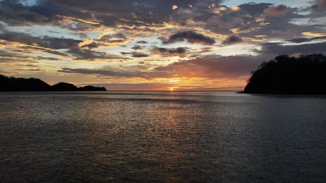 Drone flight over beach into ocean at sunset at Playa El Jobo, pacific ocean, costa rica