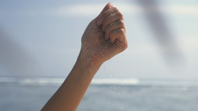 Time is running like sand through your fingers. Time, travel concept. woman hand sifting sand between fingers. unrecognisable lady enjoying paradise island near seaside in Bali, sun shine bright.
