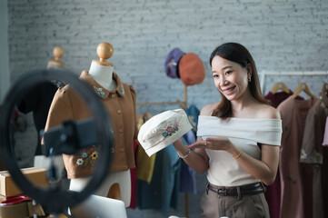 woman business vlogger owner at fashion store wave hello smartphone live streaming for sale fashion new hat