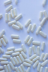 White pills are scattered on a white background. Close-up. Copy space.