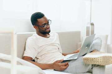 Smiling African American Freelancer Working on Laptop in Modern Home Office The young black man is...