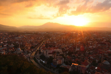 View from the Prizren Fortress onto the old town of Prizren, covered in golden sunlight during...