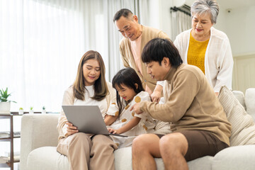 Father and mother with asian kid girl learn on laptop computer reviewing lesson study with online...