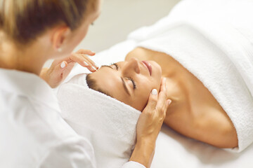 Face massage. Beautiful woman with closed eyes relaxes in spa center during facial massage....