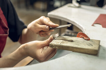 A jeweler uses a file to align a piece of jewelry in the form of a silver ring. Craft in a jewelry...