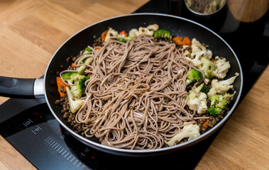 Chef at the kitchen preparing japanese buckwheat pasta with lentils