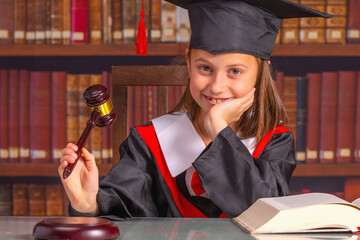 Portrait of young beautiful judge with gavel and law books against library background makes decision. Horizontal image.